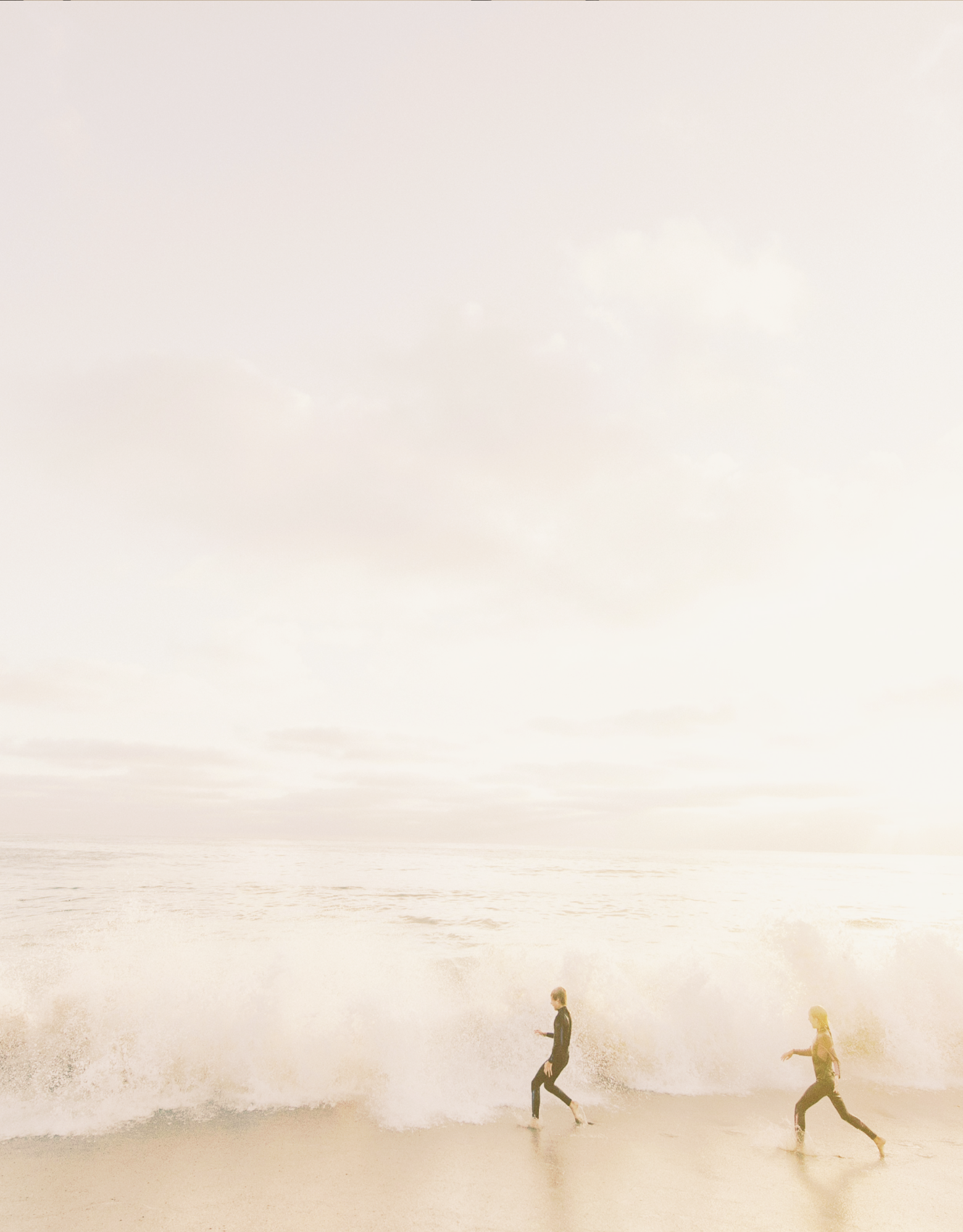 People running on beach with waves